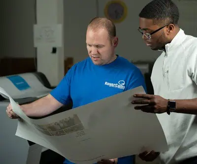 RoyerComm's print team reviewing a large format print with a customer