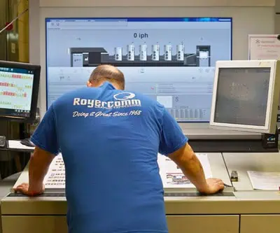 RoyerComm press operator reviewing print proofs and production controls at a commercial printing press